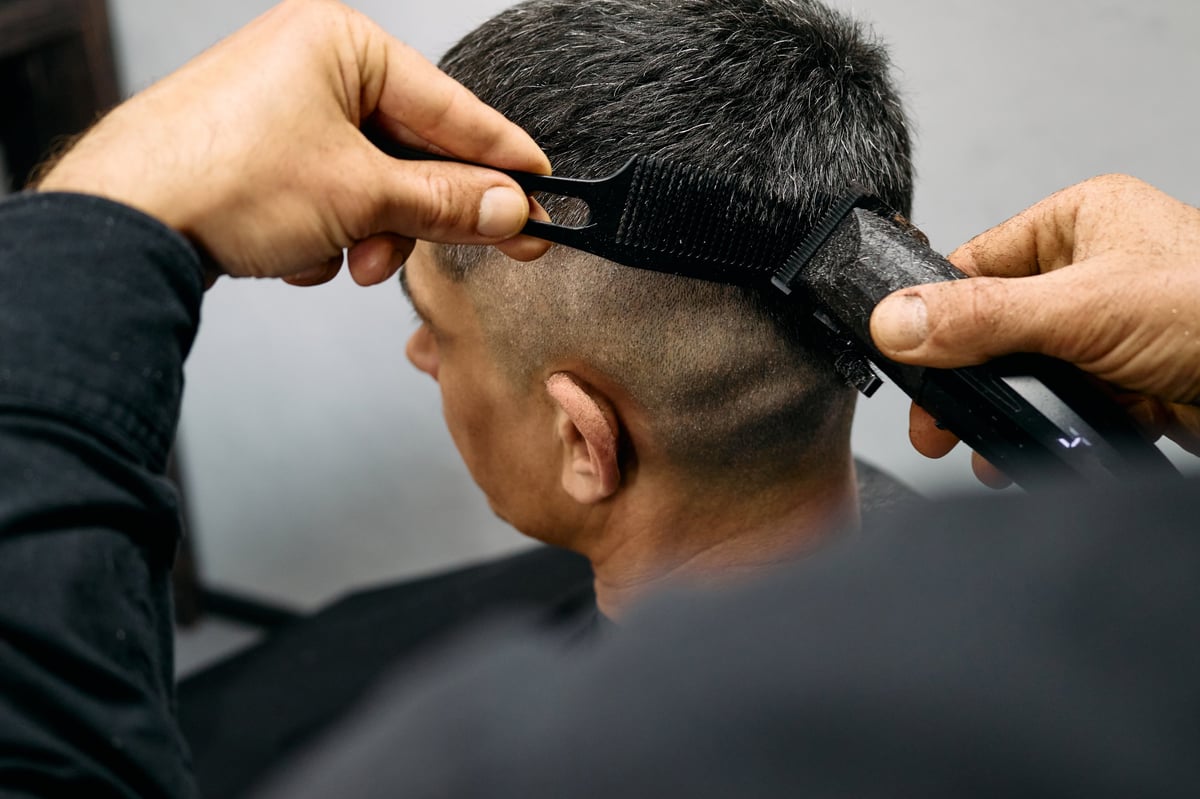 Barber working a clean fade in a bright, modern barbershop